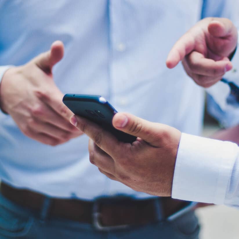 Two people gesturing to a phone.