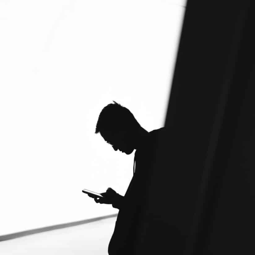 A silhouette of a person using their phone.